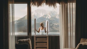 Une pièce dot ée d’une grande fenêtre donnant sur un paysage montagneux, d’un escalier en bois et de deux fauteuils confortables.