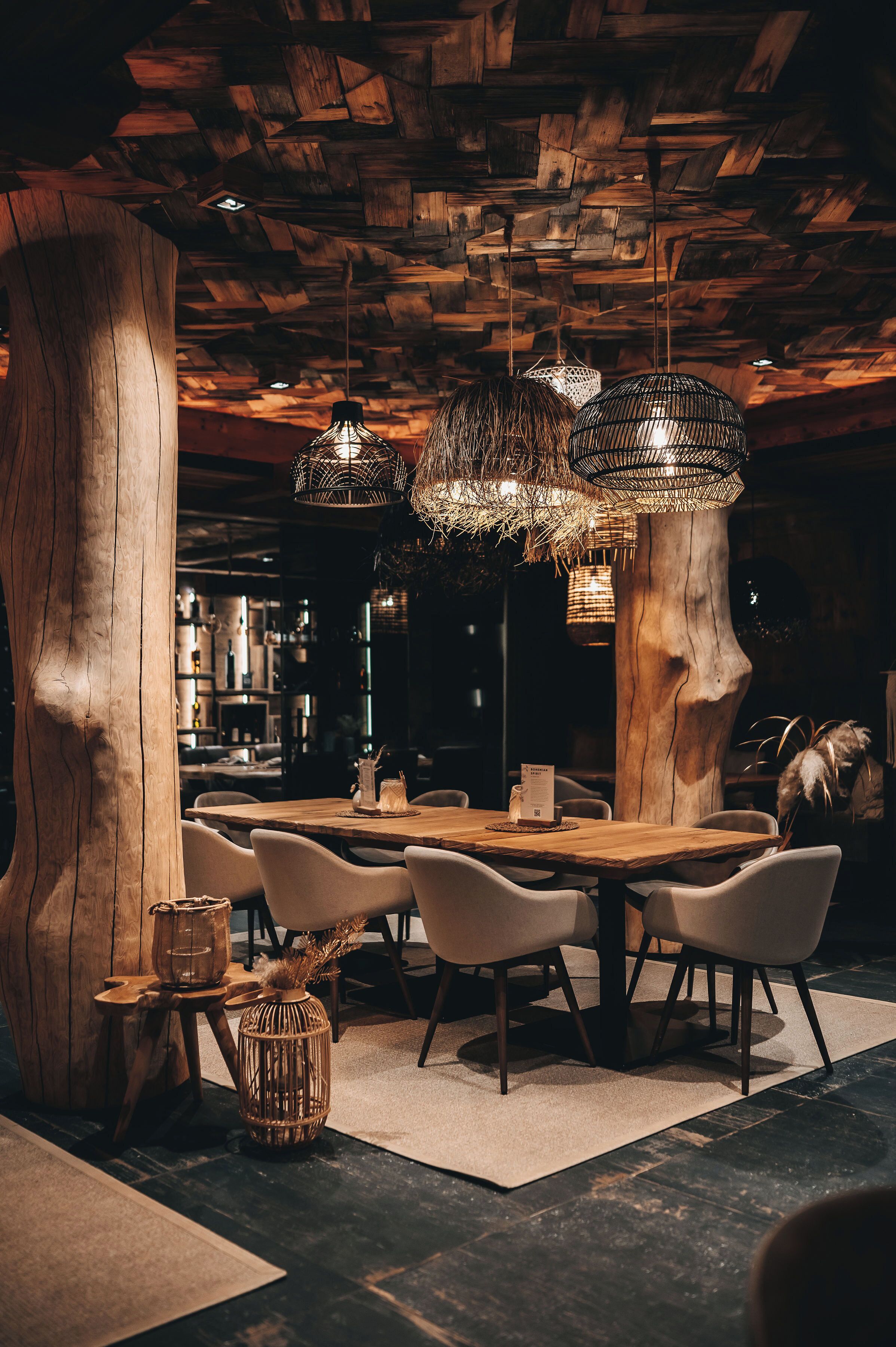 Un restaurante con techo de madera rústica, un gran tronco de árbol como centro de mesa y moderna iluminación colgante.