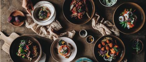 A top-down view of a dining table with various dishes, including sushi and salads, on a rustic wooden table.