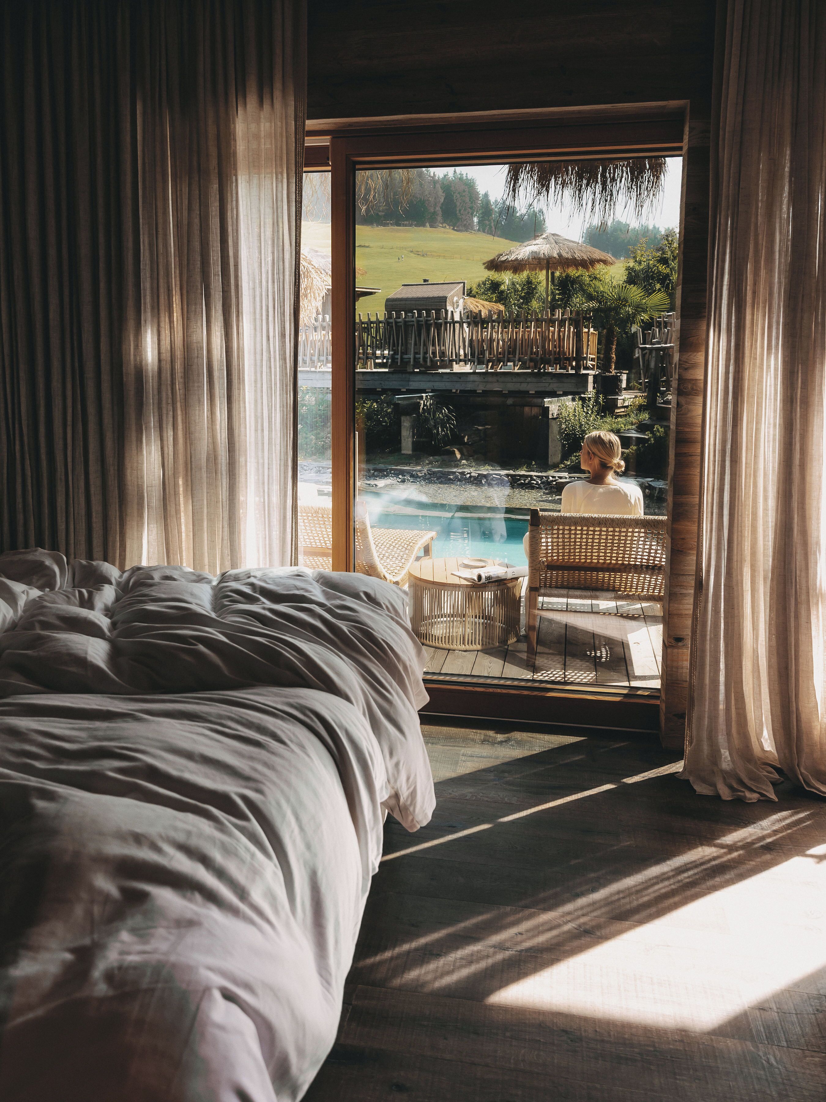 Ein Schlafzimmer mit einem großen Bett, Blick auf einen Pool und einer Holzterrasse.