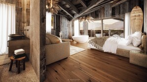Une chambre spacieuse avec un grand lit, un coin salon et une baignoire.