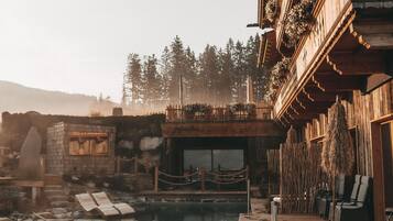 A wooden building with a pool, stone structures, and a wooden deck.