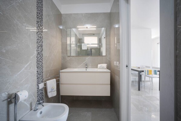 Une salle de bain moderne avec un lavabo en marbre, une cabine de douche en verre et un grand miroir.
