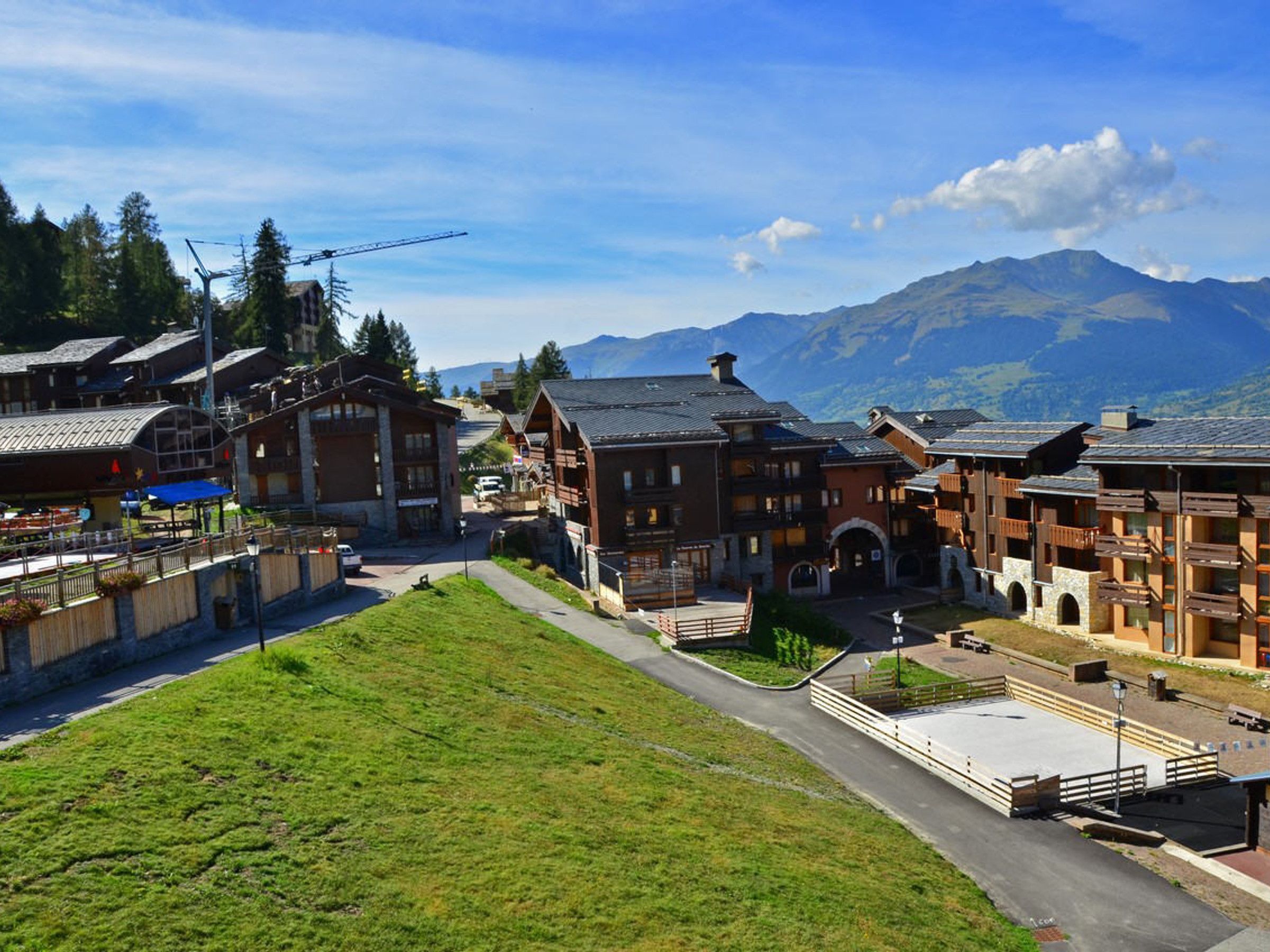 A traditional alpine village with wooden buildings, a central square, and a mountain backdrop.