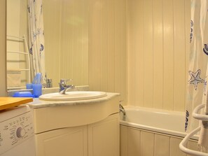A bathroom with a sink, mirror, and bathtub.