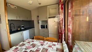 A compact kitchen with a dining table, a refrigerator, and a microwave. - Cozy 4-Person Apartment, 200m from Slopes and Shops, South-West Balcony (Crest-Voland)