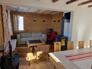 Una habitación acogedora con un sofá, dos sillones, una mesa, una silla roja, una lámpara y una estufa de leña.