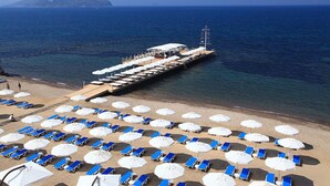 A beachside pier with rows of sun loungers and umbrellas, extending into the sea. - SUNDANCE SUITES HOTEL (Bodrum)