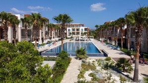 A large swimming pool surrounded by palm trees and modern buildings. - SUNDANCE SUITES HOTEL (Bodrum)