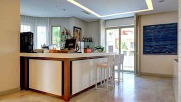 A modern kitchen with a central island, bar stools, and a large window.