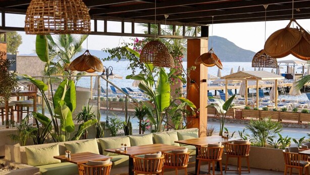 An outdoor seating area with wooden furniture, wicker lamps, and potted plants. - SUNDANCE SUITES HOTEL (Bodrum)