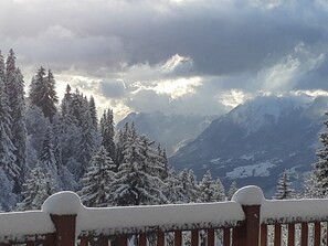 A snowy mountain landscape with a wooden fence in the foreground.