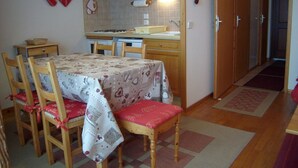 Una cocina con armarios de madera, salpicadero de azulejos, una mesa de comedor con sillas y una alfombra roja.