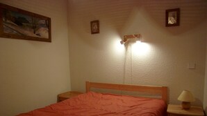 Un dormitorio con cama, mesitas de noche, lámpara y luces empotradas en la pared.