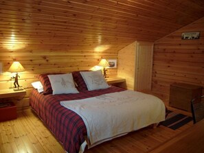 Een gezellig houten kamer met een bed, twee bedlampen en een welkomstbord.