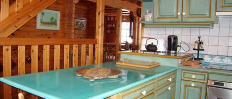 Une cuisine avec des murs en bois, un plan de travail turquoise et une cuisinière.