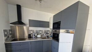 A modern kitchen with grey cabinets, a stainless steel range hood, a microwave, and a built-in oven. - Renovated 2-bedroom apartment with air conditioning, wifi, and parking in Cavalaire-sur-Mer (Cavalaire-sur-Mer)