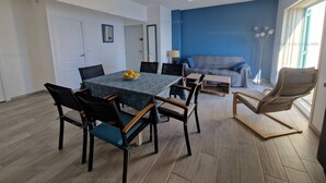 A dining area with a table set for six, surrounded by chairs, a sofa, and a floor lamp. - Renovated 2-bedroom apartment with air conditioning, wifi, and parking in Cavalaire-sur-Mer (Cavalaire-sur-Mer)