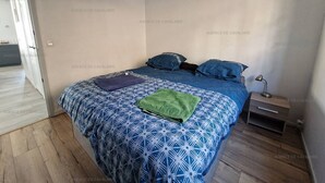 A bedroom with a bed, pillows, a nightstand, and a hanging light fixture. - Renovated 2-bedroom apartment with air conditioning, wifi, and parking in Cavalaire-sur-Mer (Cavalaire-sur-Mer)