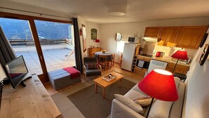 Un espacio habitable compacto con sofá, mesa de centro, zona de comedor y kitchenette.