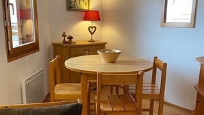Un comedor con una mesa redonda de madera, cuatro sillas de madera, una mesita auxiliar de madera con una lámpara y un bol sobre la mesa.