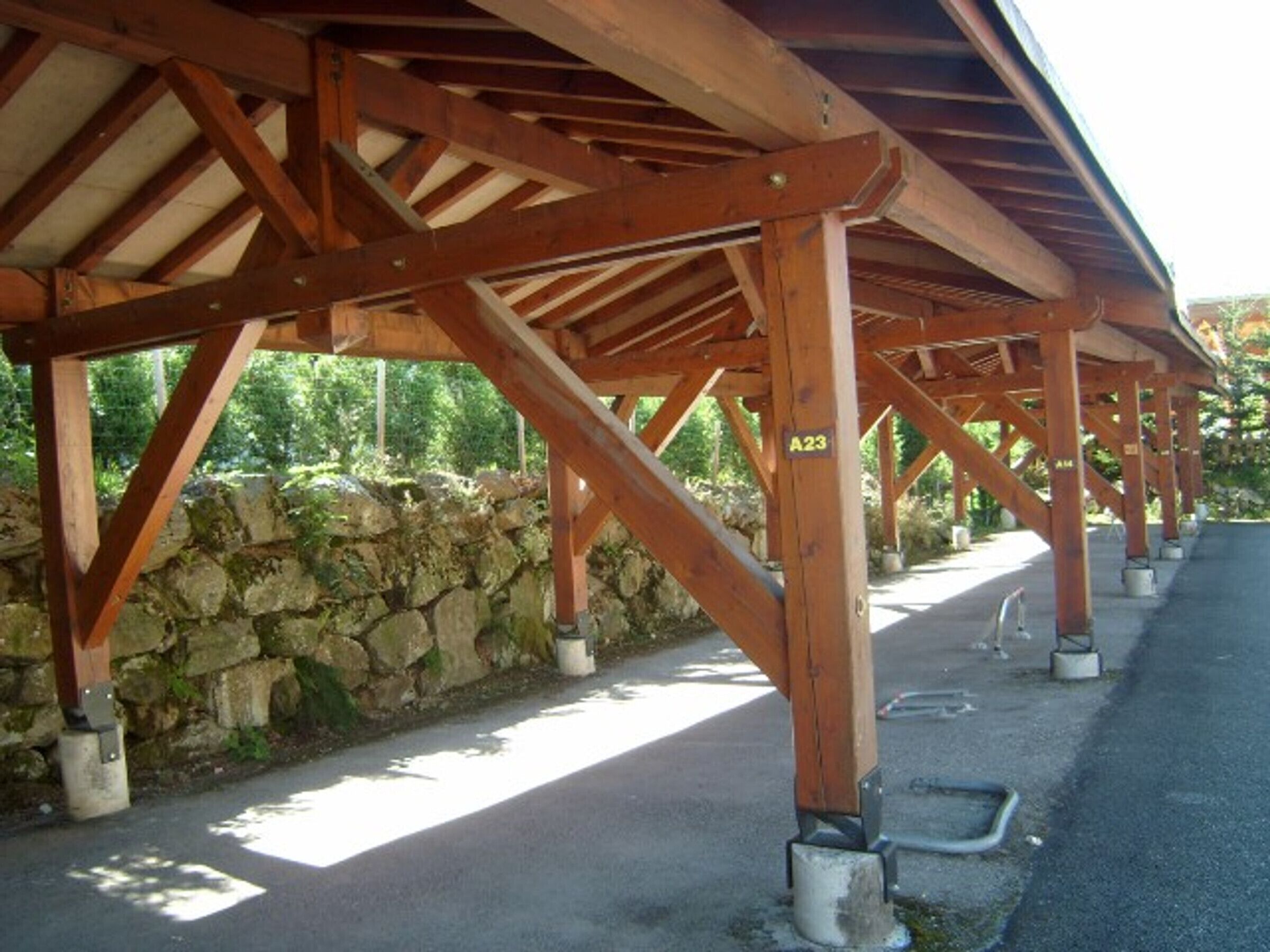 A covered outdoor area with wooden beams and a stone wall.