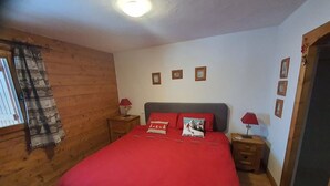 A bedroom with a large bed, wooden walls, and a window with curtains. - Cozy Apartment for 6 with Pool, Balcony, and Private Parking in Crest-Voland (Crest-Voland)