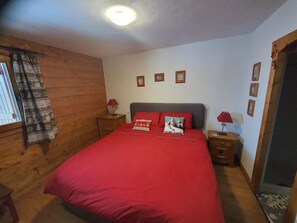 Ein Schlafzimmer mit einem großen Bett, Holzwänden und einem Fenster mit Vorhängen.