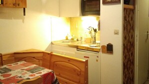 A compact kitchen with a wooden table, a refrigerator, and a microwave. - Cozy Studio-Mezzanine for 4 with Balcony, Near Slopes & Village – Pet Friendly (Crest-Voland)