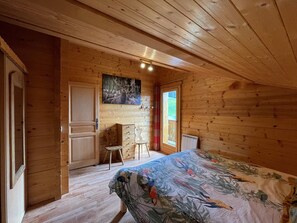 Quarto de cabana de madeira com cama, cômoda, cadeira e um quadro na parede.
