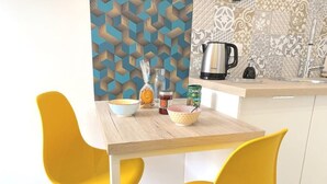 Eine moderne Küche mit einem Holztisch, gelben Stühlen und einer gemusterten Spritzschutzwand.