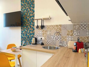 A modern kitchen with a wooden countertop, a built-in sink, a kettle, a toaster, and a coffee machine. - Studio Moderne au Cœur de Rochefort - Vivez L'élégance et le Confort (Rochefort)