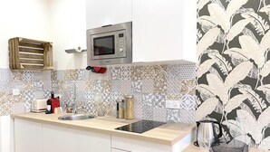 Una cocina moderna con microondas, tostadora, pileta y salpicadero con diseño.