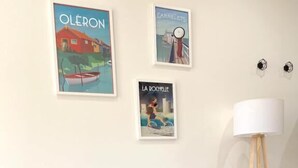 Una sala de estar moderna con un sofá gris, una mesa de centro redonda de madera y tres obras de arte enmarcadas en la pared.