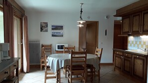 Un coin repas avec une table ronde et des chaises, un four à micro-ondes et une fenêtre avec des rideaux.