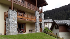 Un bâtiment à deux étages, doté de piliers en pierre, de balcons en bois et d’une pelouse devant.