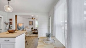 Une cuisine spacieuse avec des meubles blancs, un îlot central en bois et un coin repas comprenant une table et des chaises.