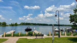 A riverside dock with a bench, a boat, and a lamp post.
