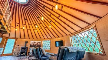 Un intérieur chaleureux avec un plafond arrondi, des murs en bois et un coin salon doté de fauteuils en cuir.