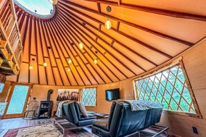 Un interior acogedor con techo abovedado, paredes de madera y una zona de estar con sillones de cuero.