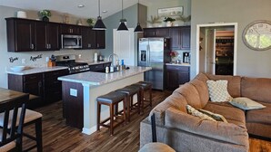 A modern kitchen with dark cabinets, a central island, and pendant lighting. - St. John's, 3 bdrm, 2 bath, 2022 built home. 10% off military, breast cancer (The Villages)