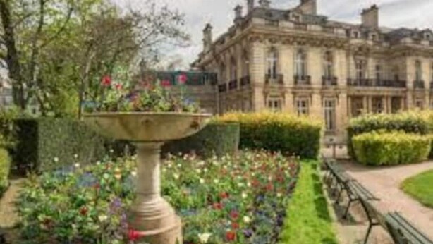 A formal garden with a central fountain, manicured hedges, and a classical building in the background. - Studio Moderne Proche Champs Elysée (Paris)