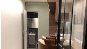 A modern kitchen with wooden cabinets, a stainless steel sink, and a built-in oven. - Studio Moderne Proche Champs Elysée (Paris)
