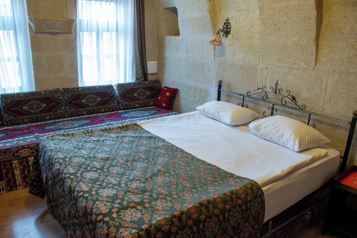 A bedroom with a large bed, a smaller sofa bed, and a patterned bedspread.