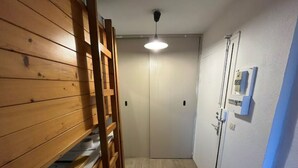 En smal hall med träpanel på ena sidan, en vit dörr längst ner och en lampa i taket.