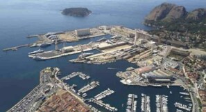 Vue aérienne d’une marina côtière avec de nombreux quais et des bateaux.