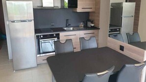 A compact kitchen with a refrigerator, oven, sink, and a dining area with chairs. - Beachside Studio with Terrace, A/C, Parking - Sleeps 4 in Fréjus (Fréjus)