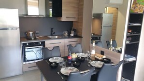 A compact kitchen with modern appliances, a dining area with a table set for two, and a bookshelf with books and decorative items. - Beachside Studio with Terrace, A/C, Parking - Sleeps 4 in Fréjus (Fréjus)