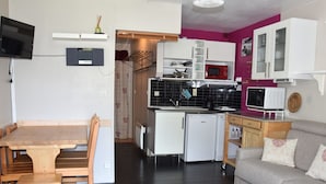A compact living space with a dining area, kitchenette, and seating area. - South-facing studio 4 pers, near center, terrace (Pralognan-la-Vanoise)