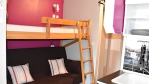 A bunk bed with a wooden ladder, a brown sofa with striped pillows, and a kitchen area with a sink and utensils. - South-facing studio 4 pers, near center, terrace (Pralognan-la-Vanoise)